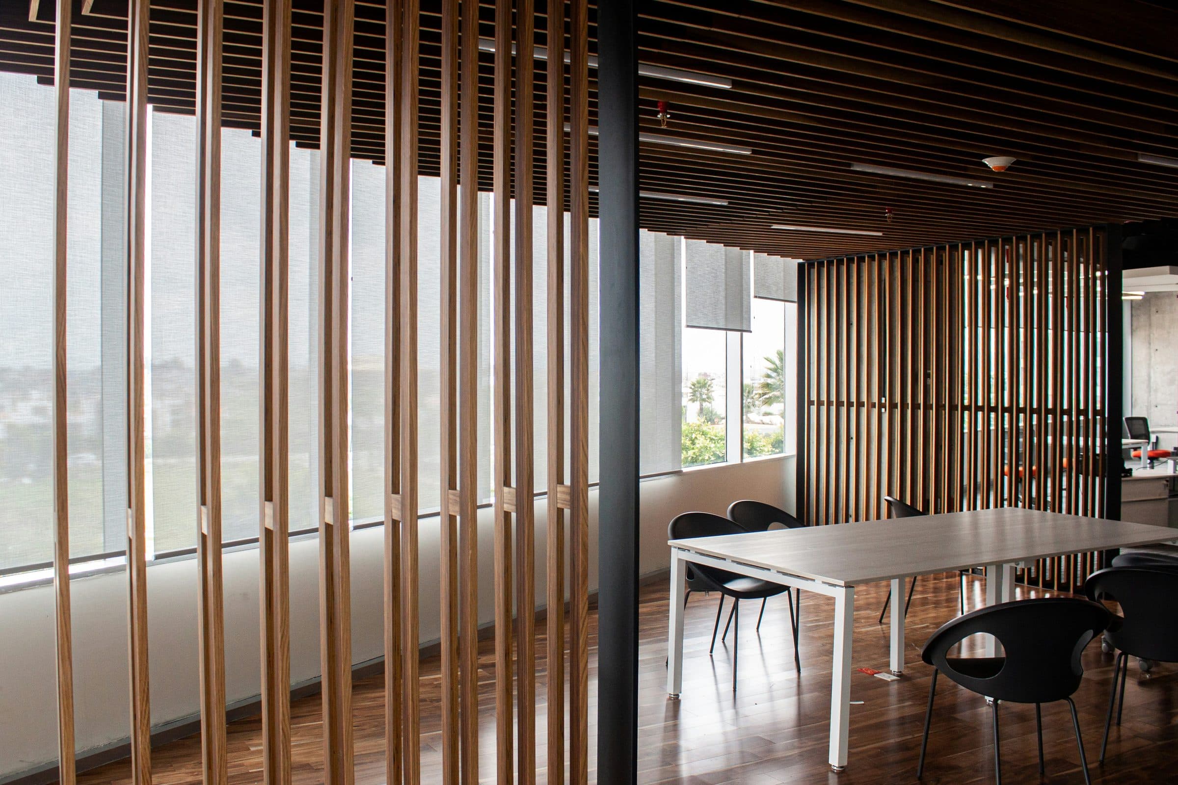 Open-plan office with warm wood slat partitions and floor-to-ceiling windows